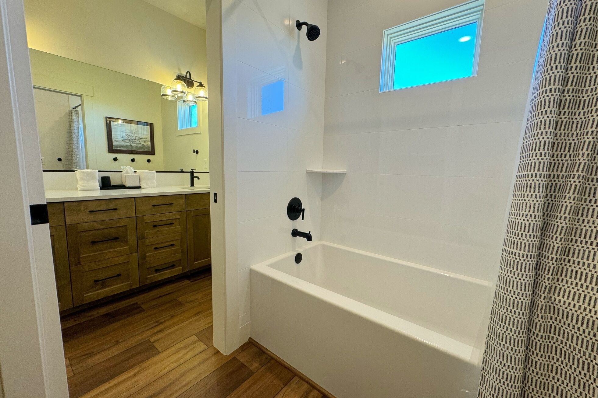 A modern bathroom with a wooden vanity, a bathtub, and a shower.
