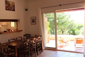 Enjoy meals in this dining area with a table and chairs, adjacent to a patio with lounge seating and a lush plant.