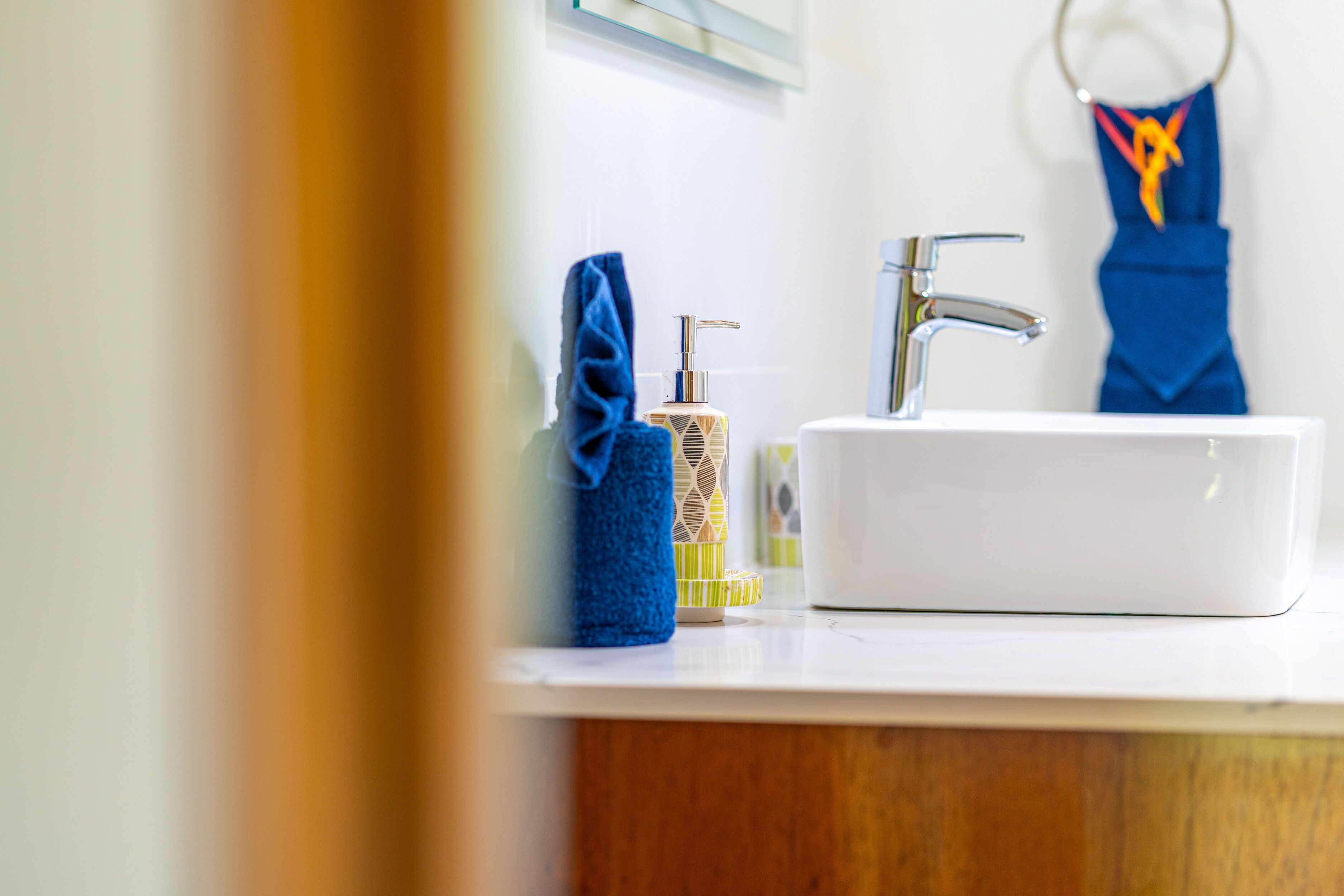 A bathroom with a white sink, a blue towel, and a soap dispenser.