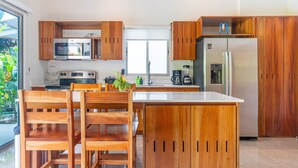 A modern kitchen with wooden cabinets, a central island, and built-in appliances. - Two bedroom. Ojochal. Private pool. Minutes to beach (Ojochal)