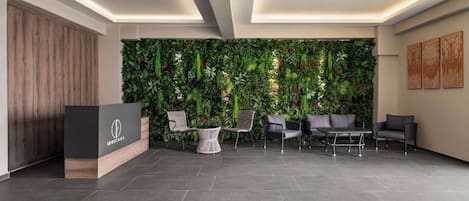 A reception area with a wooden reception desk, seating, and a green vertical garden wall.
