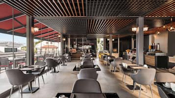 Un café moderne doté d’un bar central, de grandes fenêtres et de mobilier contemporain.