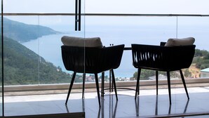 Two chairs with cushions facing a large window overlooking a mountainous landscape and a body of water. - Ramada by Wyndham Fethiye Oludeniz (Fethiye)