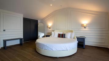 Una cama redonda grande con ropa blanca, dos mesitas de noche y lámparas fijadas a la pared.