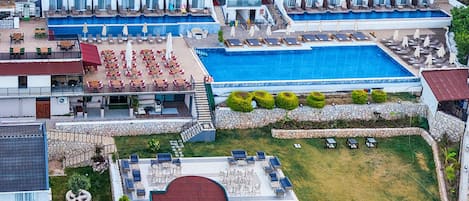 A hotel with multiple balconies, a swimming pool, and outdoor seating areas.