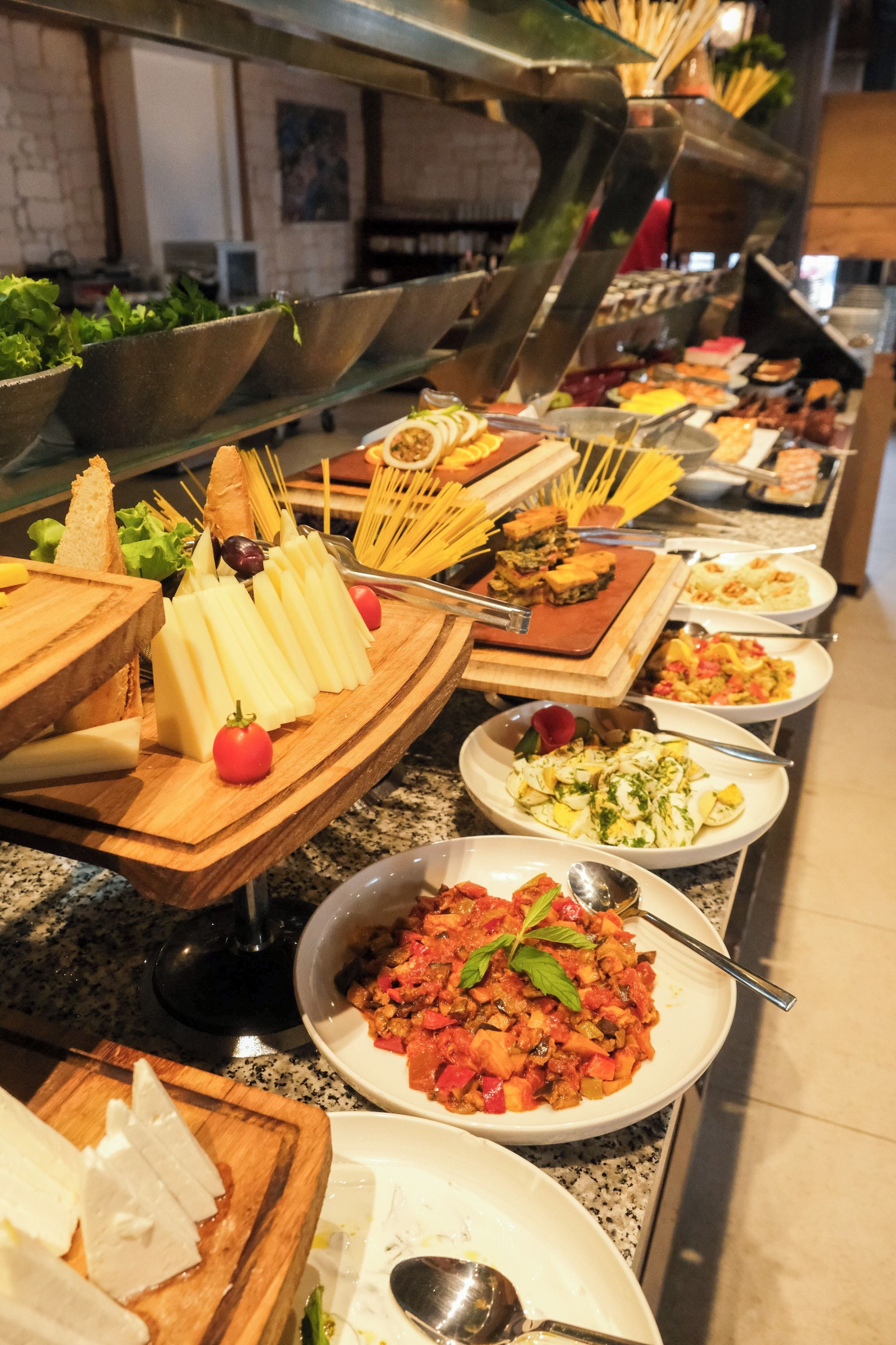 A buffet with various food items including pasta, salads, and bread.