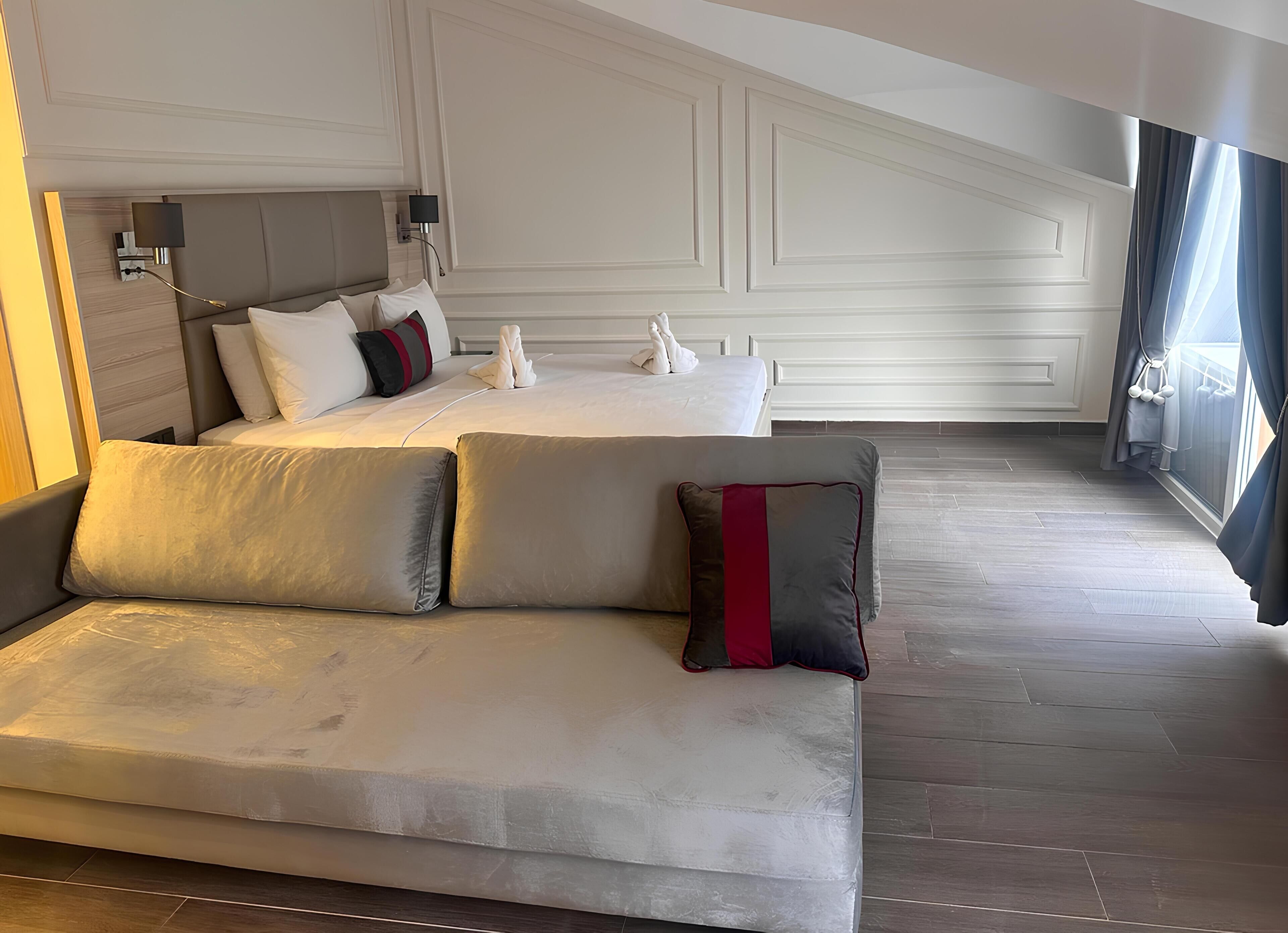 Una habitación de hotel moderna con una cama grande, un sofá y vistas a la ciudad.