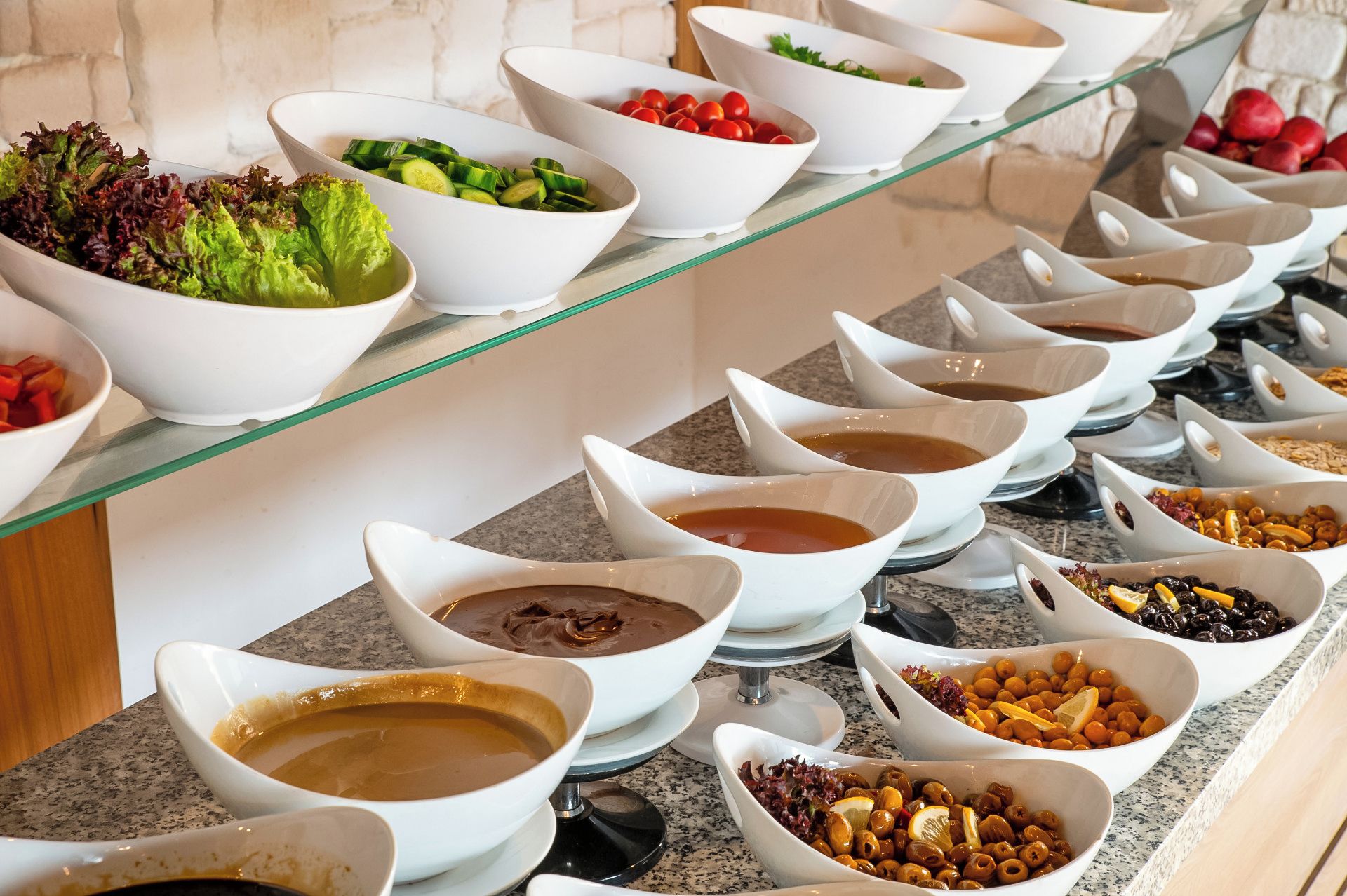 A buffet with various food items and condiments arranged on a glass shelf.