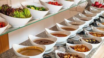 A buffet with various food items and condiments arranged on a glass shelf.