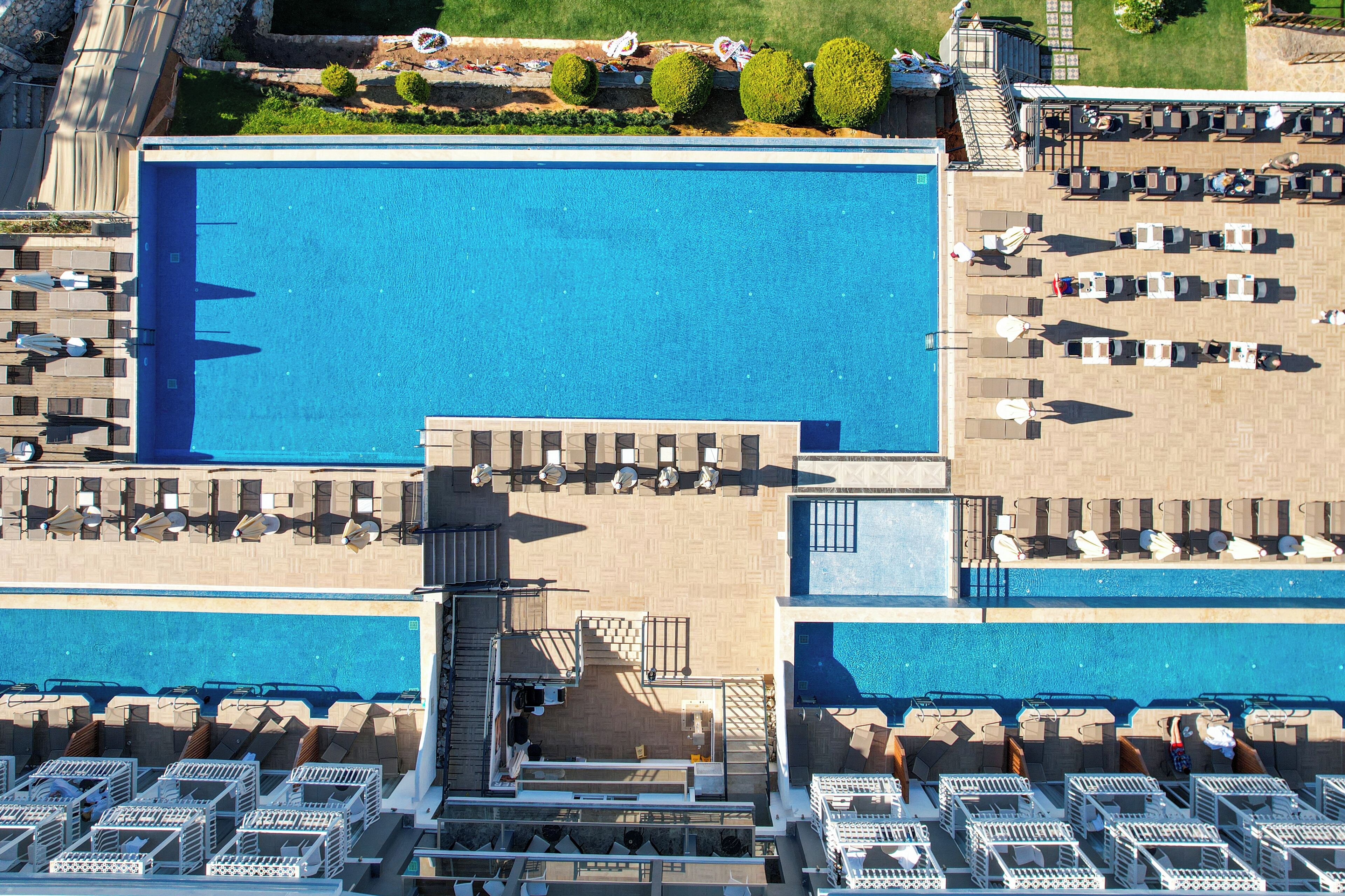 A large rectangular pool with multiple lounge areas and sunbeds.