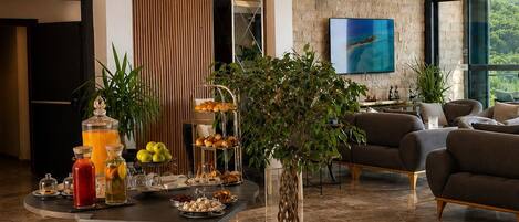 A modern living room with a round wooden table, a large potted plant, and a flat-screen TV mounted on the wall.