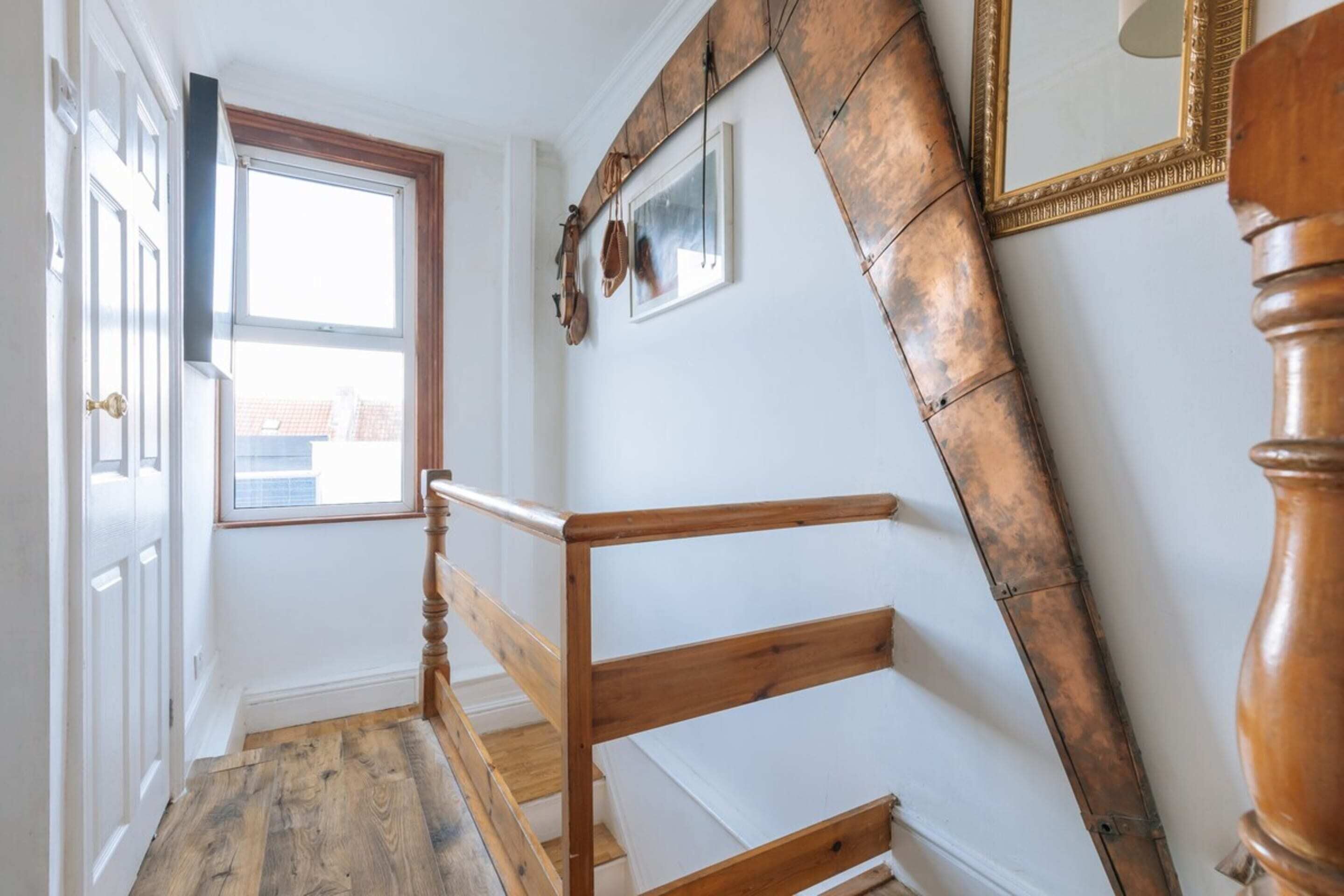 A staircase with wooden handrails and a view of the outside through a window.
