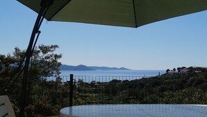 A terrace with a view of the sea, a chair, and a table under a large umbrella. - Le Repaire des Pirates (Pietrosella)