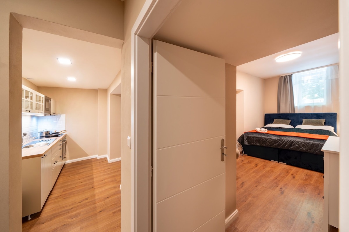 A compact room with a bed, a bedside table, and a window.