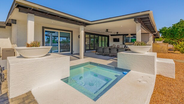 Ein modernes Haus mit Pool, Sitzgelegenheiten im Freien und einer überdachten Terrasse.