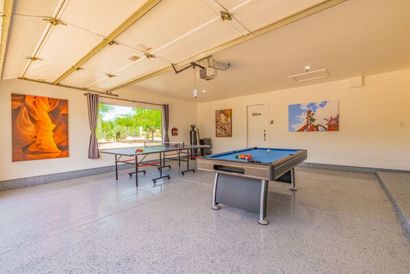 Een ruime binnenspeelruimte met een tafeltennistafel, een pooltafel en een beamer.