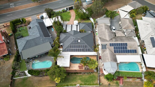 An aerial view of a residential area with two swimming pools, solar panels, and a dock with boats. - River front property, huge yard and pool, 2km from the beach.  (Mermaid Waters)