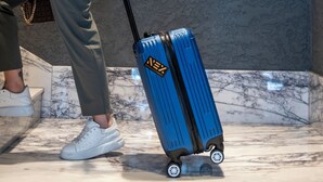 A person walking with a suitcase in front of a wall with a circular pattern. - Nex Hotel & Spa İstanbul (Istanbul)