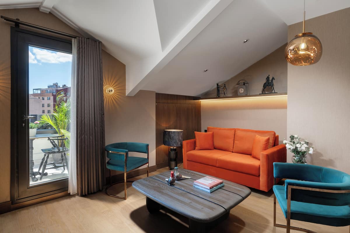 A modern living room with a sofa, chairs, a coffee table, and a view of the city through a large window.