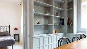 Une chambre à coucher comprenant un lit, une table de chevet, une lampe et une grande armoire blanche avec des étagères.
