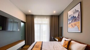 Une chambre d’hôtel avec un grand lit, un bureau, un téléviseur fixé au mur et un tableau au-dessus du lit.