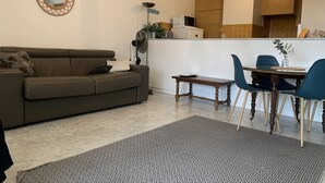 A living room with a sofa, a coffee table, and a dining area with chairs and a table. - Beau Studio à Antibes (Antibes)