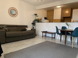 A living room with a sofa, a coffee table, and a dining area with chairs and a table. - Beau Studio à Antibes (Antibes)