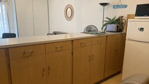 A kitchen with wooden cabinets, a white countertop, a Samsung refrigerator, a wall-mounted mirror, and a sign indicating a view of the sea. - Beau Studio à Antibes (Antibes)