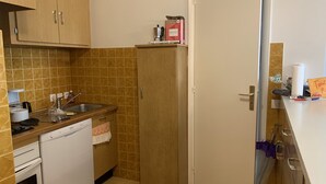 A compact kitchen with wooden cabinets, a white dishwasher, and a stainless steel sink. - Beau Studio à Antibes (Antibes)