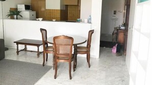 A dining area with a round table and four chairs, a kitchen in the background, and a doorway leading to another room. - Beau Studio à Antibes (Antibes)