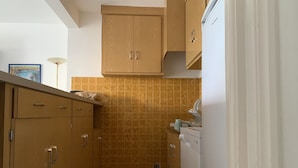 A kitchen with wooden cabinets, a white refrigerator, and a tiled backsplash. - Logement Entier : Appartement - Antibes, France (Antibes)