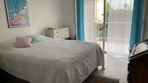 A bedroom with a bed, a dresser, a poster, and a view of the outdoors. - Logement Entier : Appartement - Antibes, France (Antibes)