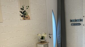 A modern living room with a dark sofa, a decorative wall piece, a small side table with a vase, and a shower curtain with a sign indicating a plage 200m.