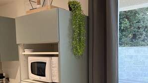 A kitchen with a microwave, a small refrigerator, and a window with curtains.
