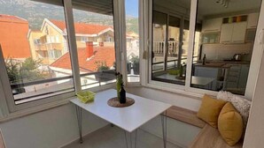 A balcony with a white table, a potted plant, and a sofa with cushions. - Lamada One Bedroom Apartment (Budva)