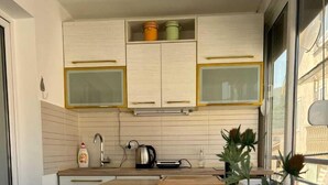 A modern kitchen with white cabinets, a wooden countertop, and a large window. - Lamada One Bedroom Apartment (Budva)
