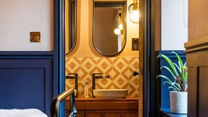A narrow hallway leading to a bathroom with a wooden vanity, a large mirror, and a potted plant. - The Queen's Chew Magna (Bristol)