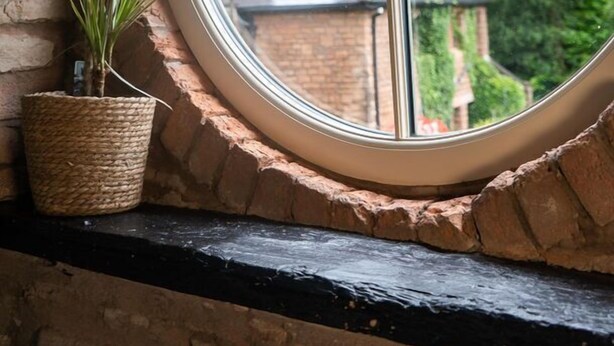 A window with a view of a brick building and greenery. - The Queen's Chew Magna (Bristol)