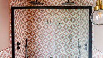 A bathroom with patterned walls, a black tiled floor, a white toilet, and a shower with a gold faucet.