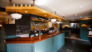 A bar area with a wooden counter, shelves of bottles, and a chalkboard menu. - The Queen's Chew Magna (Bristol)