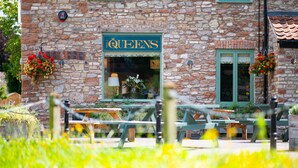 A stone building with a sign reading "QUEENS" and outdoor seating. - The Queen's Chew Magna (Bristol)
