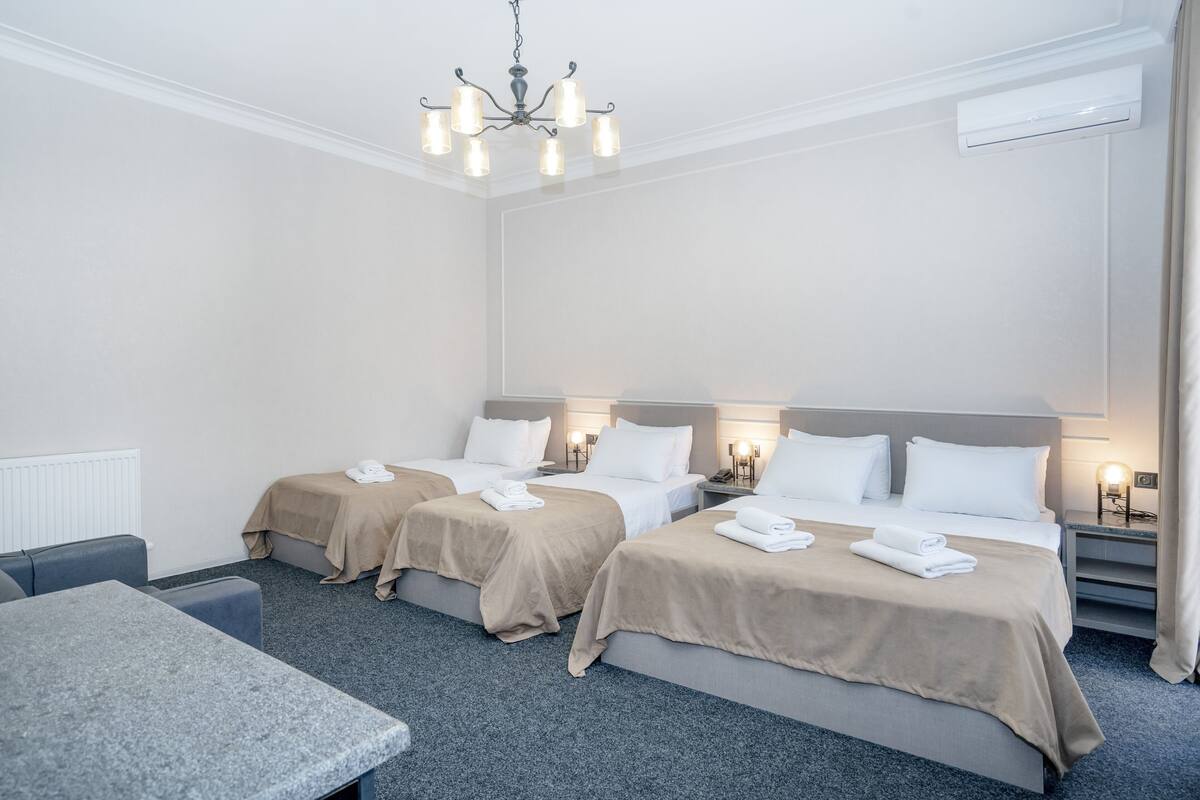 A hotel room with two beds, a table, and a chandelier.