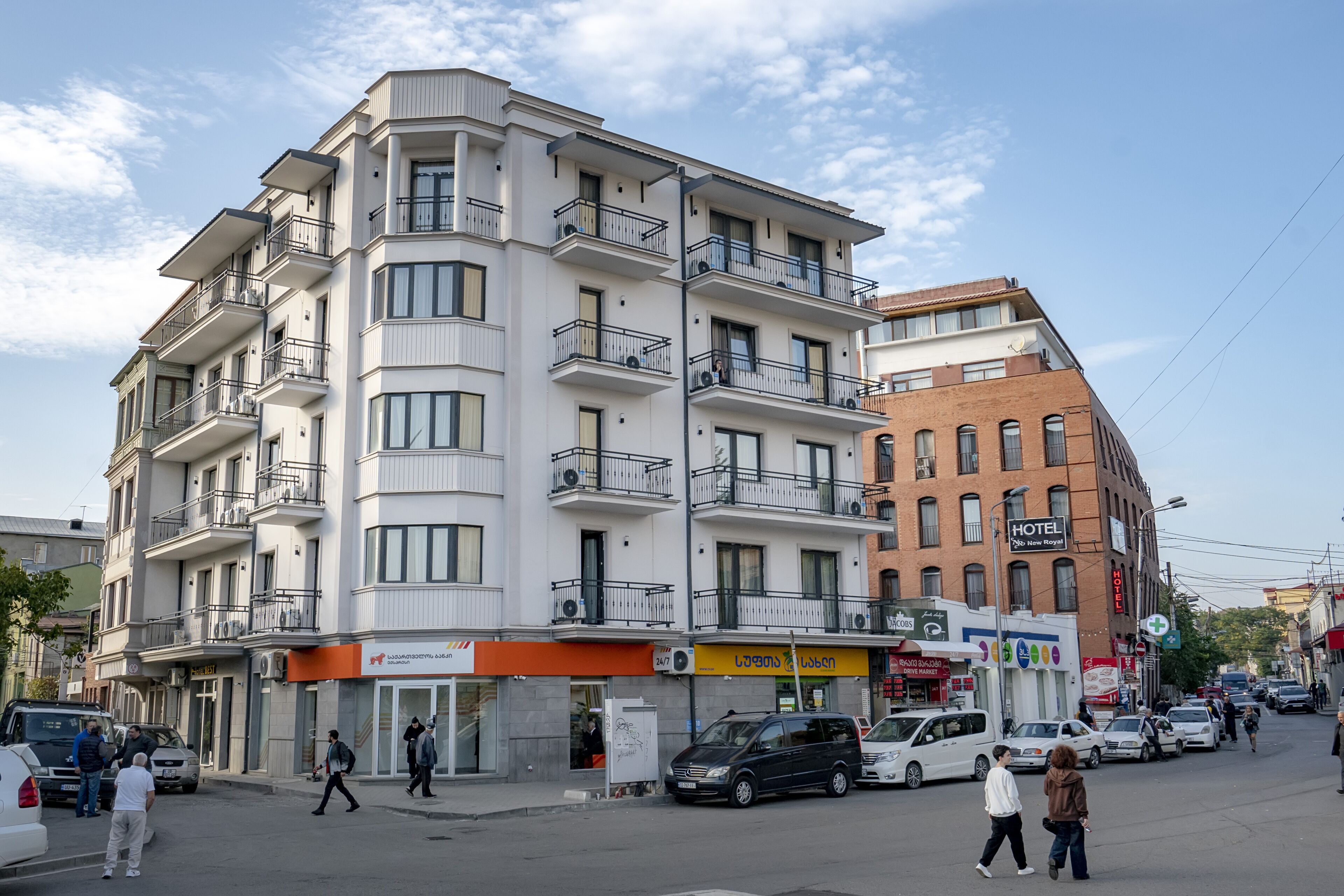 A multi-story hotel with balconies, a visible sign for a hotel, and a storefront with a sign in a foreign language.