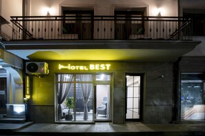 A hotel entrance with a neon sign reading "HOTEL BEST," a glass door, and a balcony with railings. - Hotel Best Tbilisi (Tbilisi)