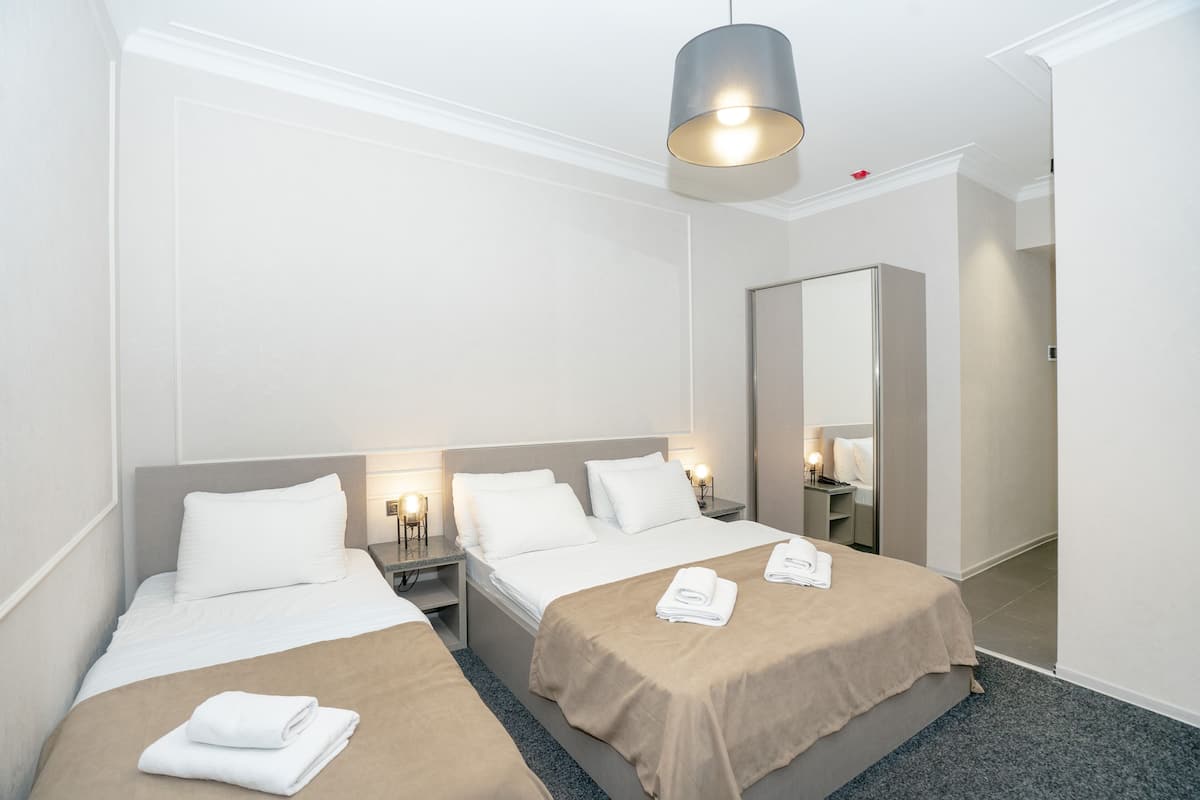 A hotel room with two beds, a large mirror, and a hanging light fixture.