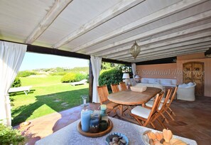 Enjoy a tranquil outdoor dining experience in a charming, sheltered space with a round table and comfortable seating.