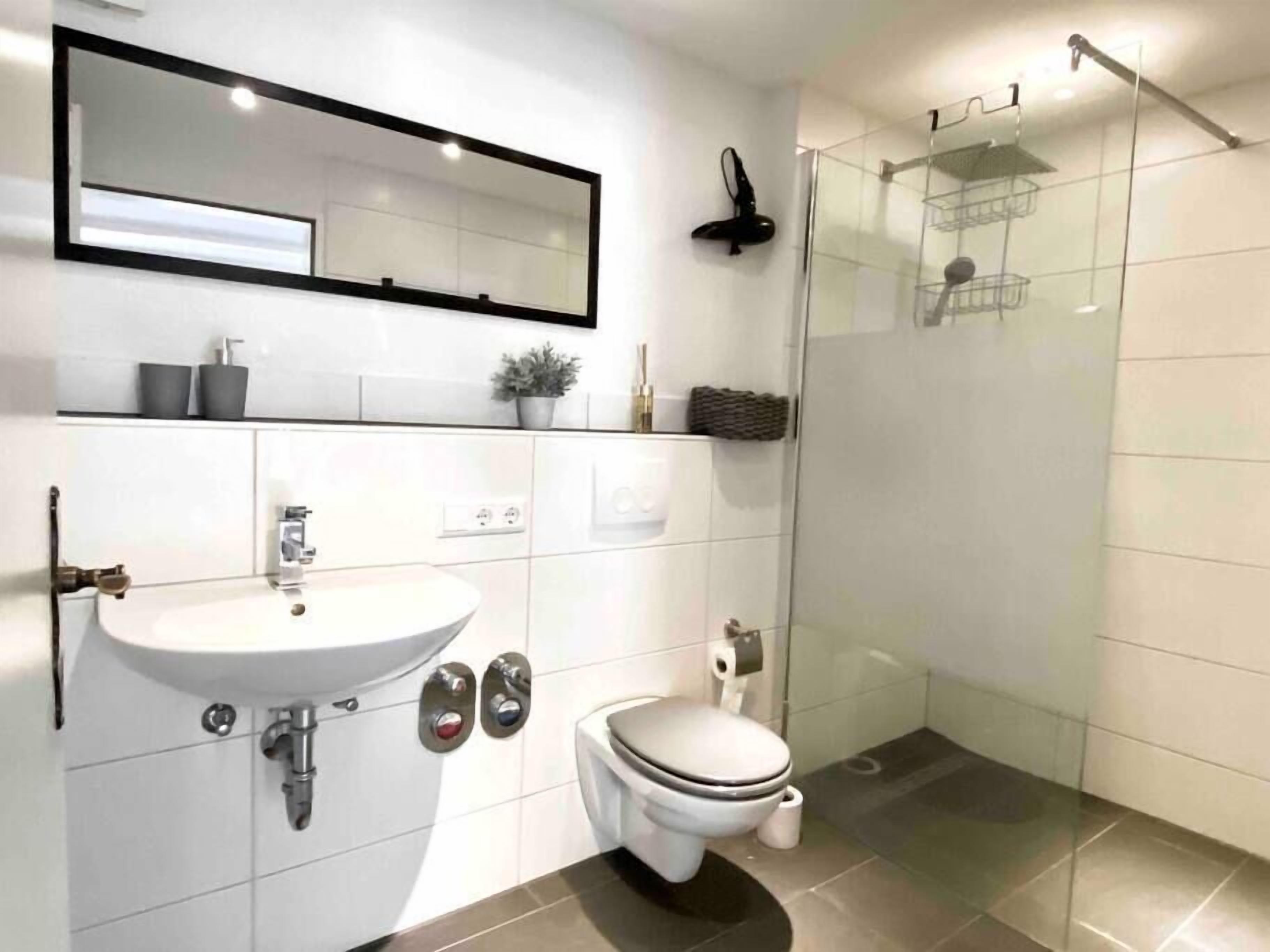 Un baño moderno con lavamanos, inodoro y cabina de ducha de vidrio.