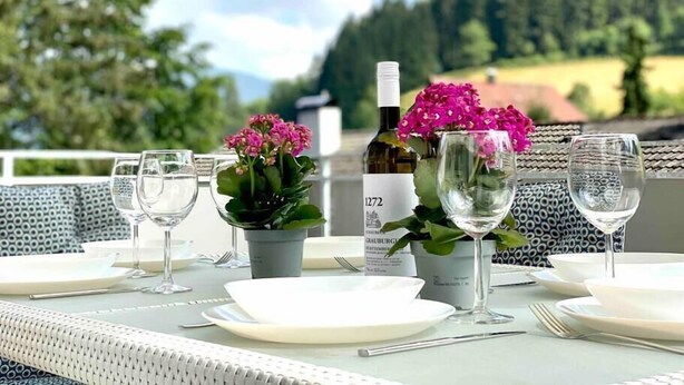 A table set outdoors with wine glasses, a bottle, and flowers. - *Schwarzwald-Haus mit Sauna* (Elzach)