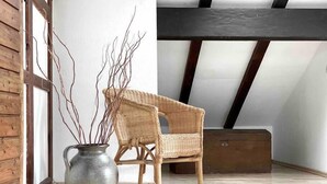 A room with a wooden chair, a large vase with branches, and a sloped ceiling with exposed beams. - *Schwarzwald-Haus mit Sauna* (Elzach)