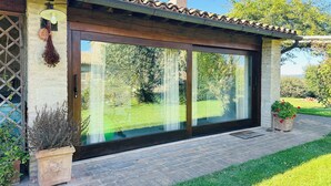 A house with a large sliding glass door, a brick patio, and a garden. - Milva's Nest Countryside (Umbria)